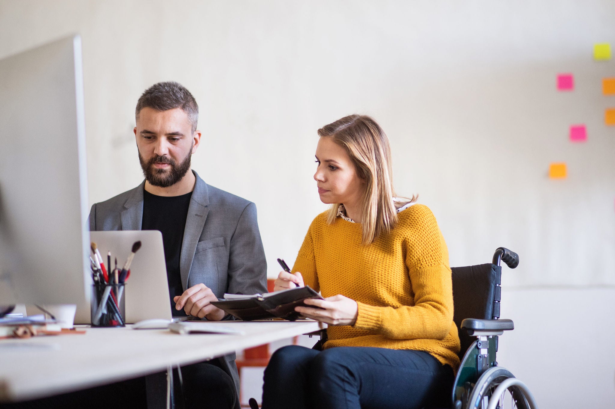 ey-woman-in-wheelchair-reviews-work-with-colleague