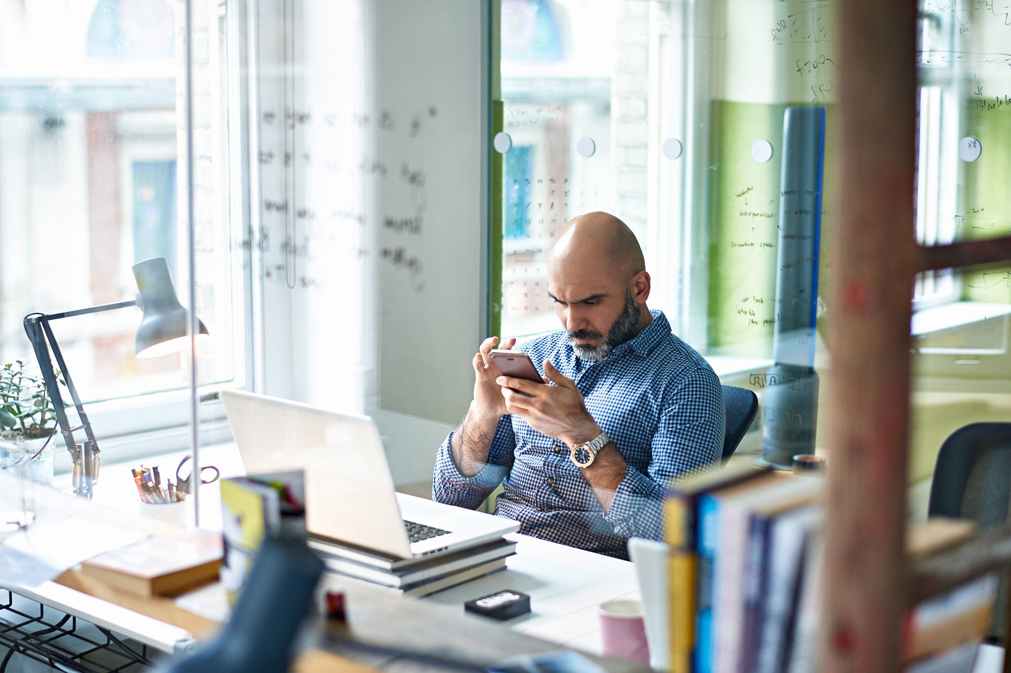 Businessman using mobile phone at desk in modern office.