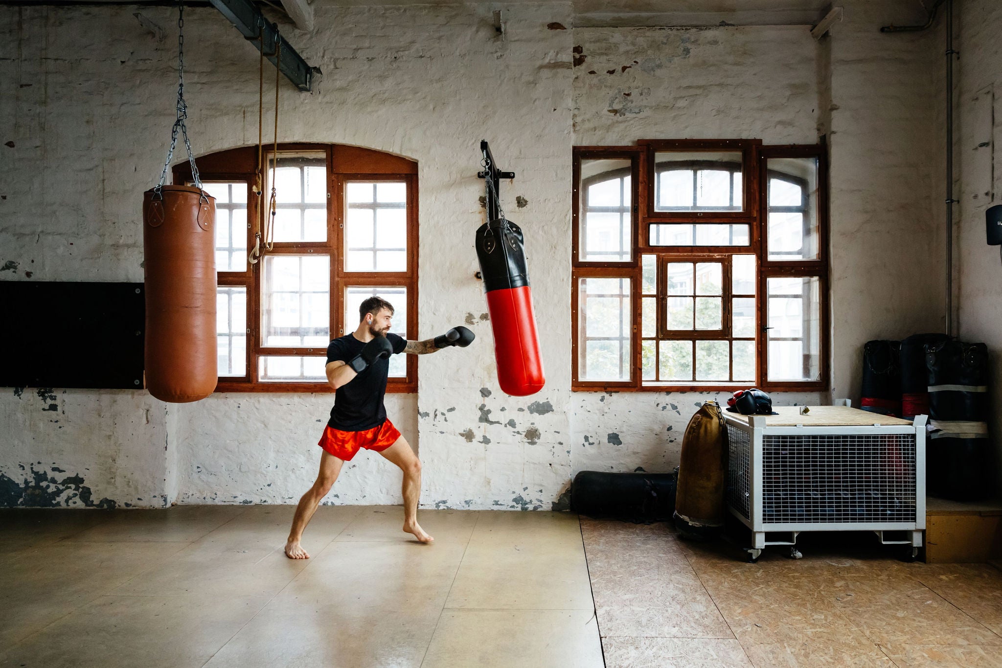 Male muay thai boxer training on sandbag in a gym