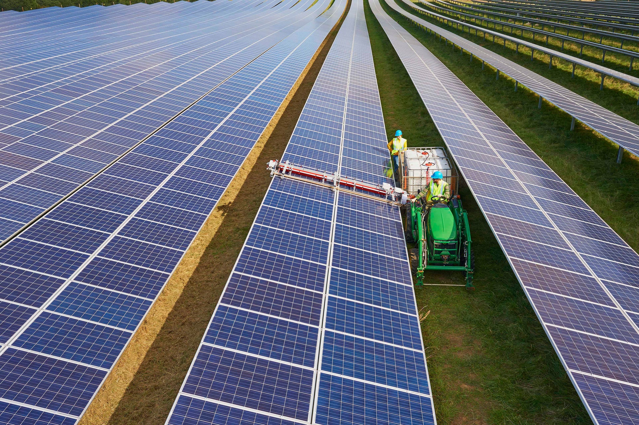 Young farmers using heavy duty equipment to clean solar panels in their farm