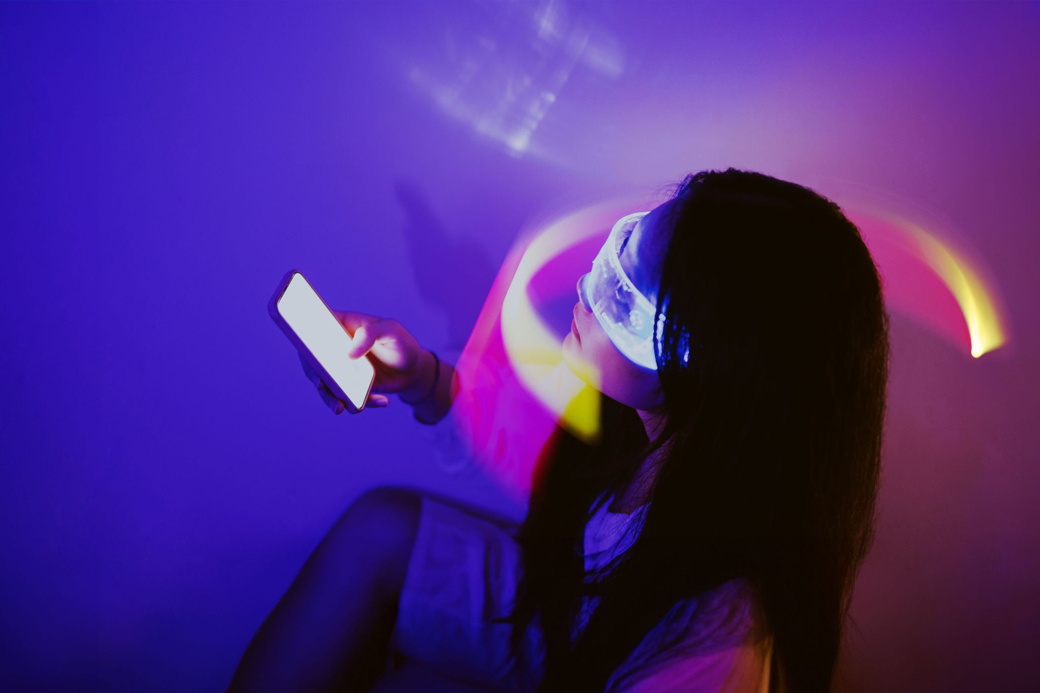 Person using smartphone surrounded by beams of light