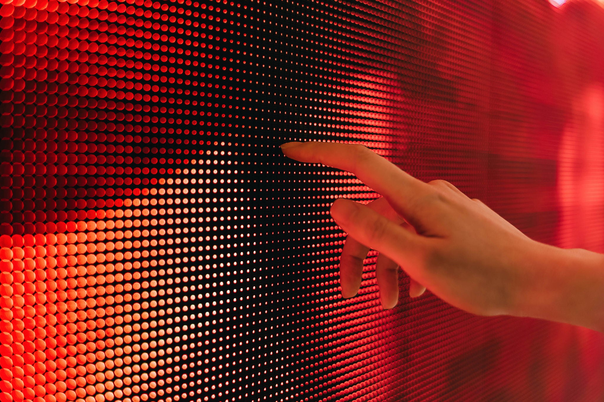 Close up of woman's hand touching illuminated LED display screen, connecting to the future