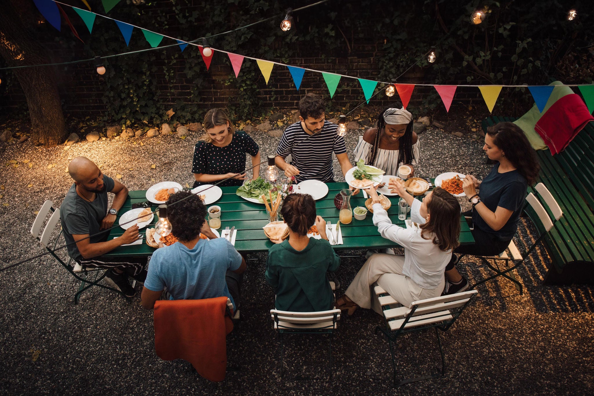 High angle shot of friends eating at a long garden table