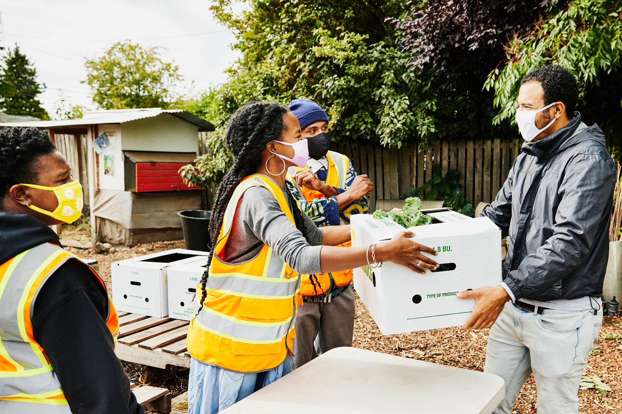 Man receiving CSA box from volunteer at community garden