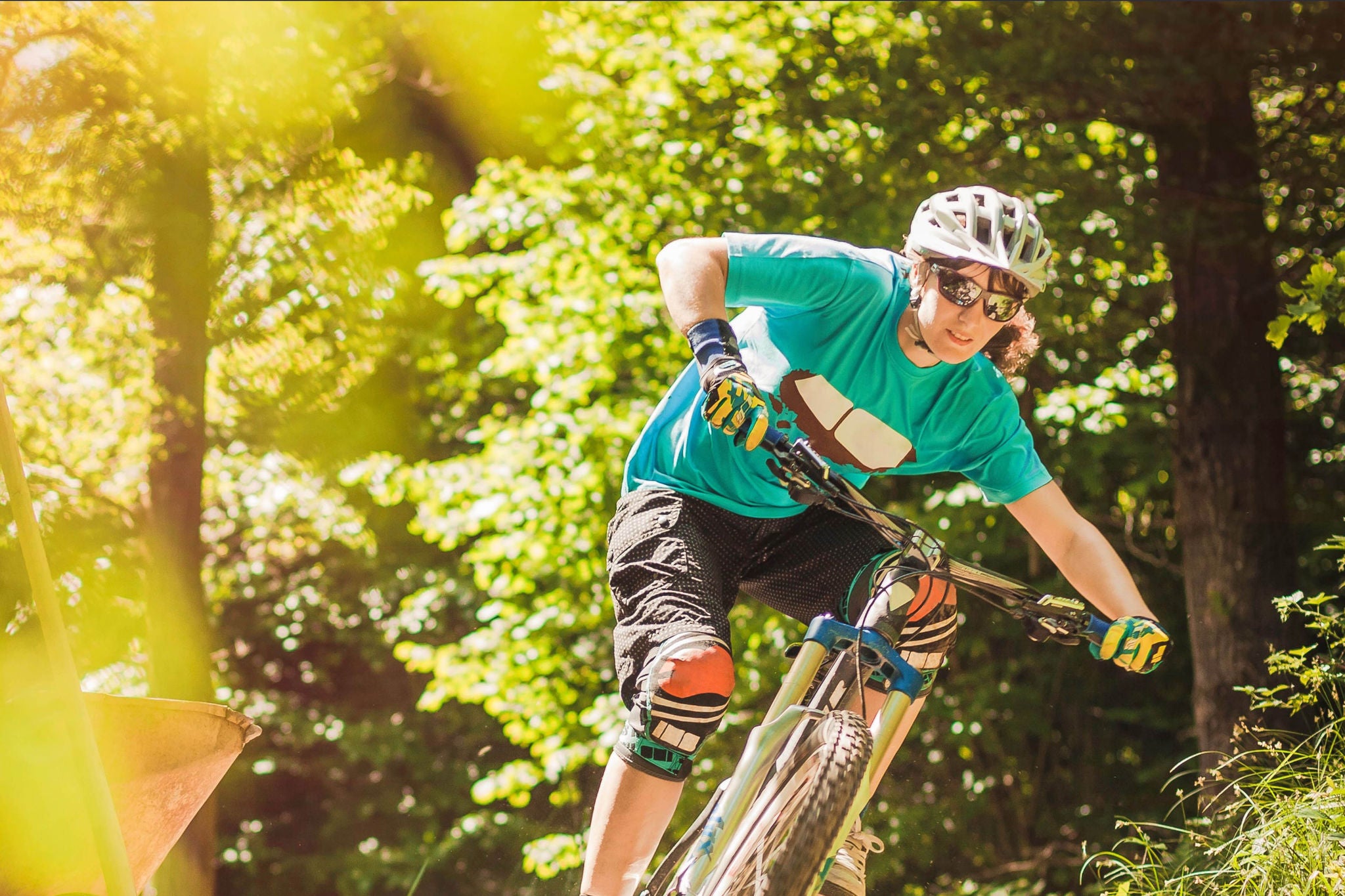 Person on a bike with sunglasses and helmet cycling through the forest