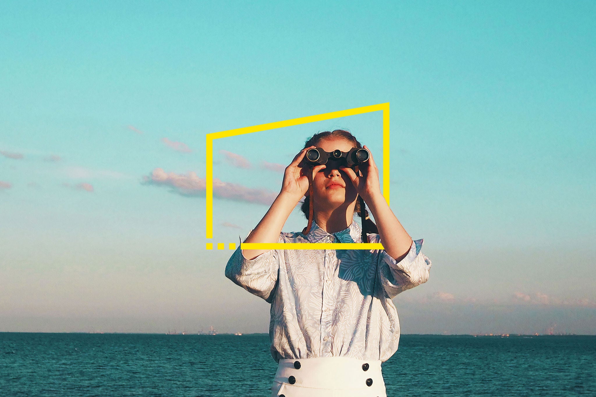 Young woman standing against sea and sky with binoculars