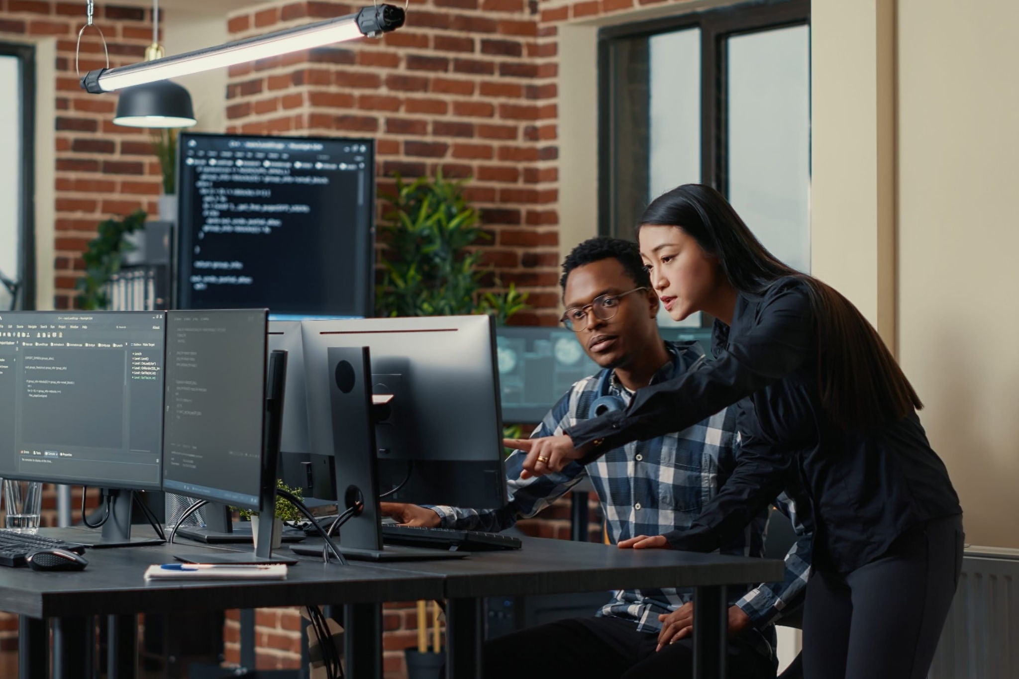 Office colleagues discussing by pointing to computer