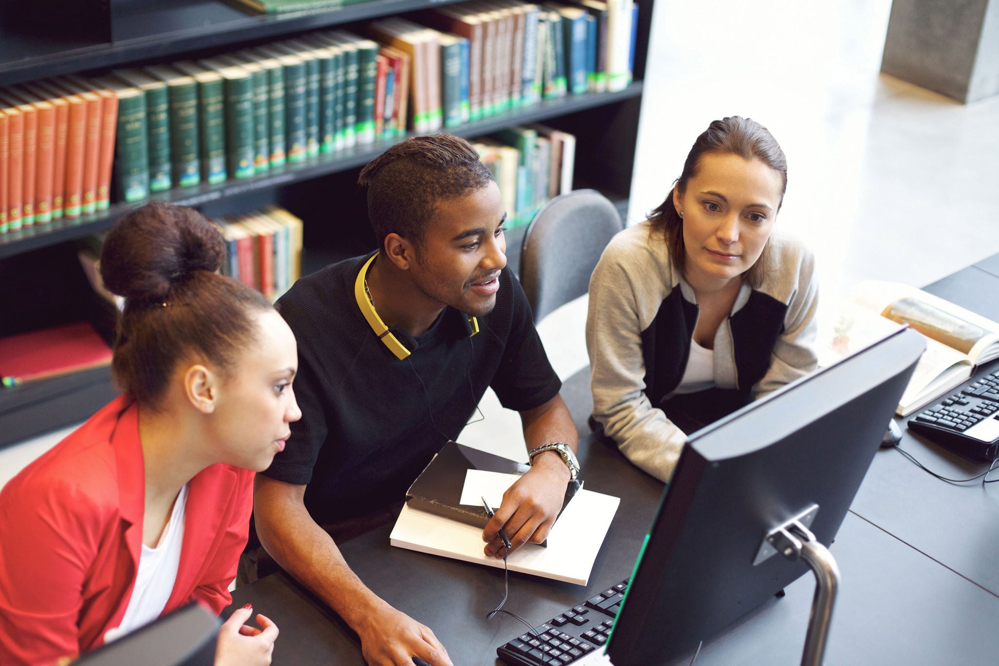 Students collaborating at computer in library.