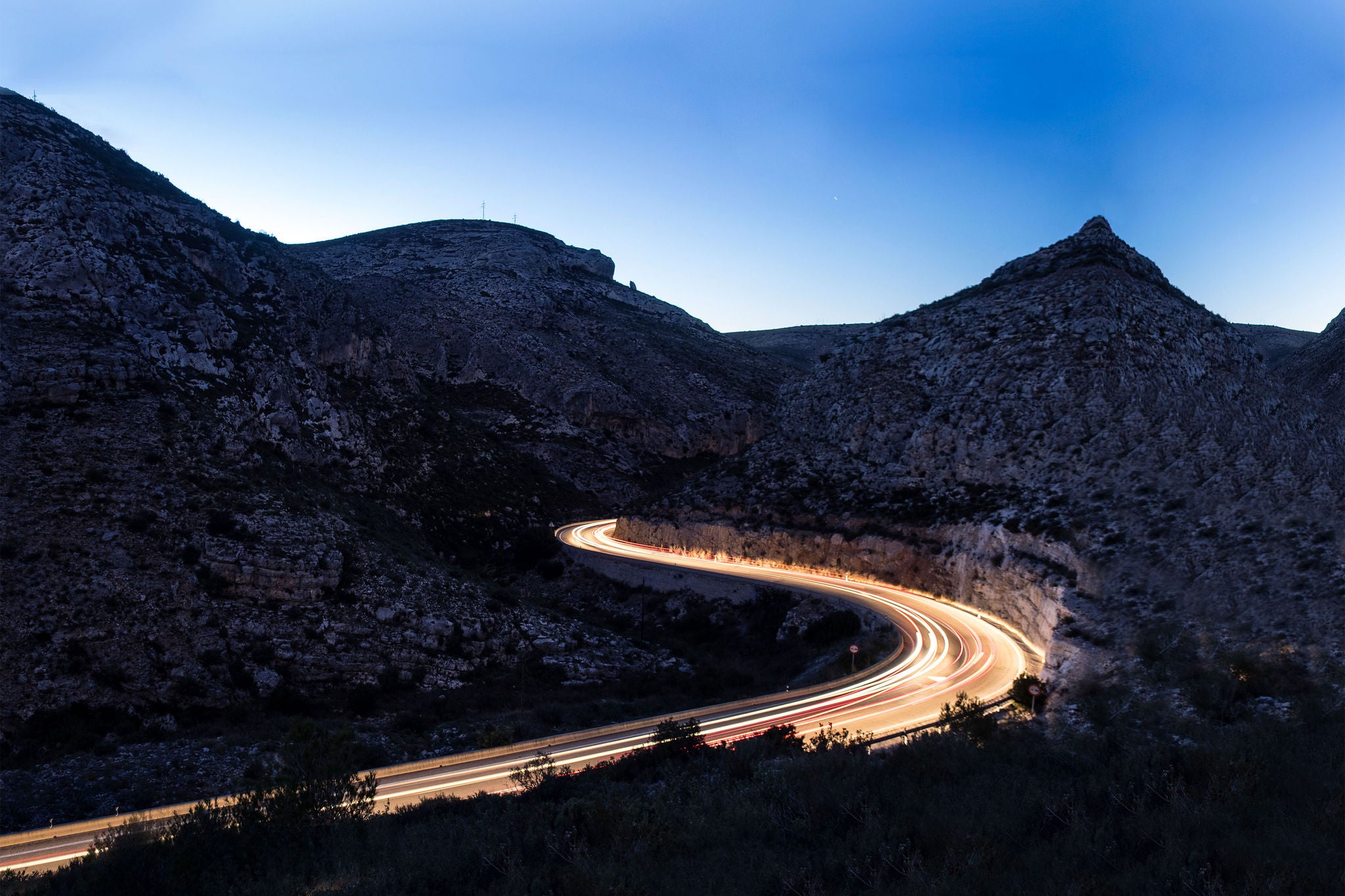 Lights of vehicles circulating along a road between mountains and ravines