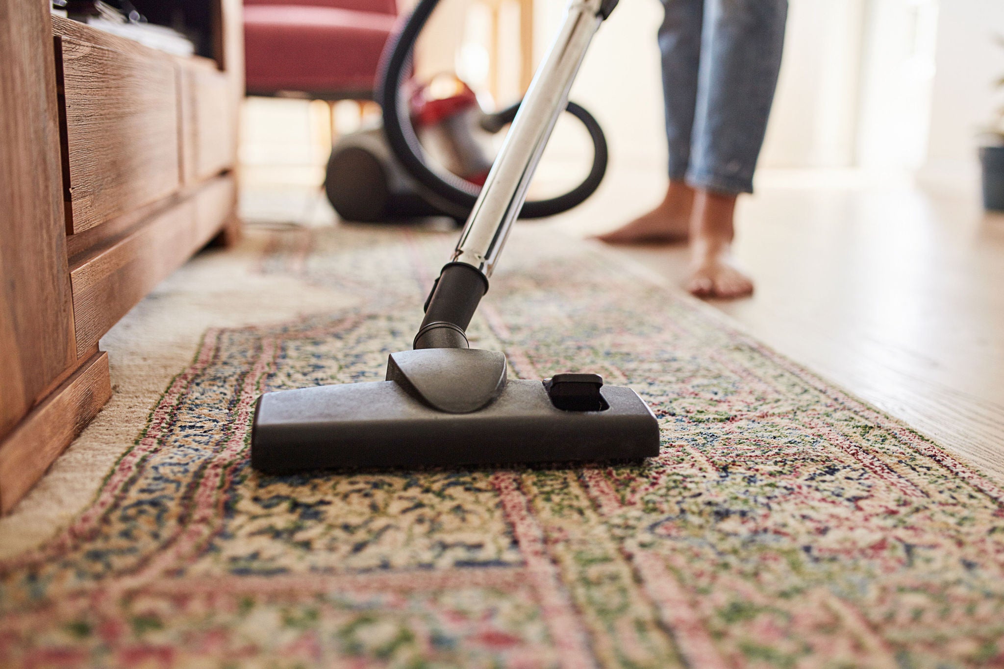 Aufnahme einer jungen Frau, die zu Hause das Wohnzimmer saugt.