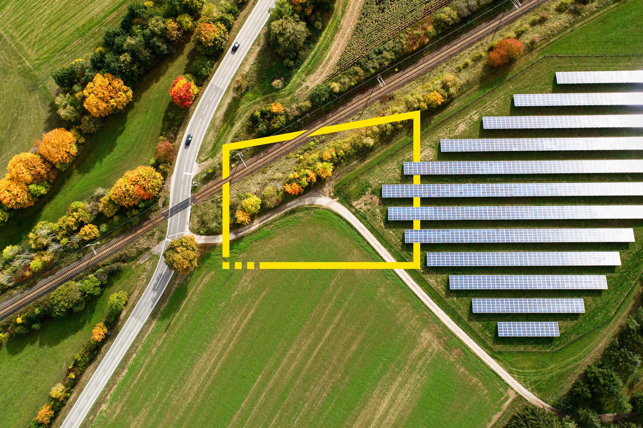 Aerial view of a highway crossing railroad tracks in autumn 