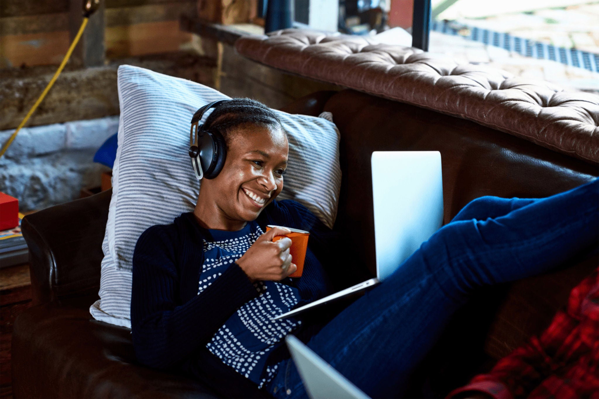 A women with the headphone over the head looking at the laptop.