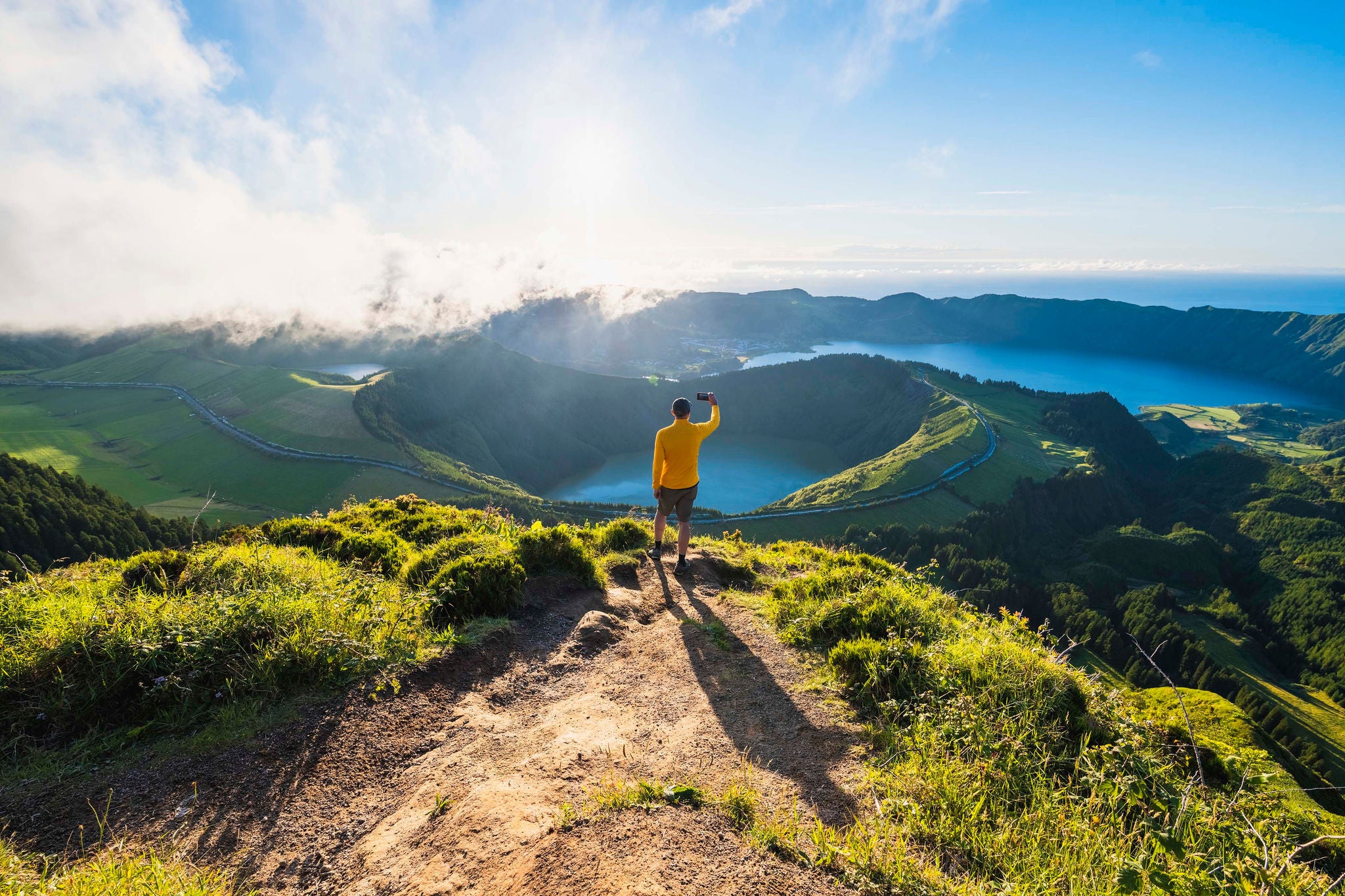 Man on top of a mountain photographing volcanoes in Sao Miguel, Azores