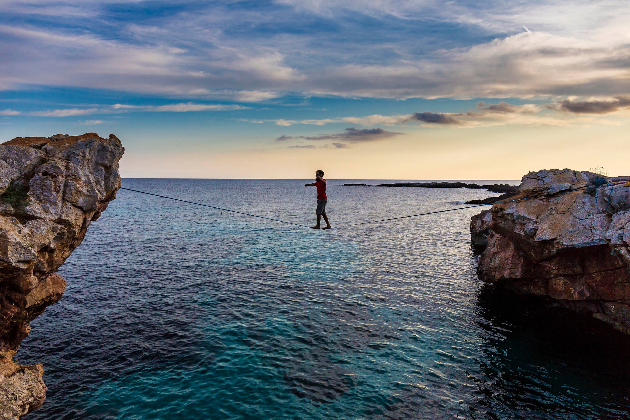 Man practicing slackline over the sea in Minorca Balearic Islands Spain