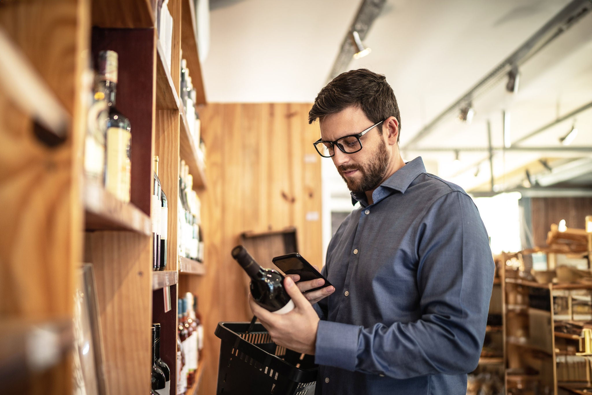 Homem tirando foto de uma garrafa de vinho