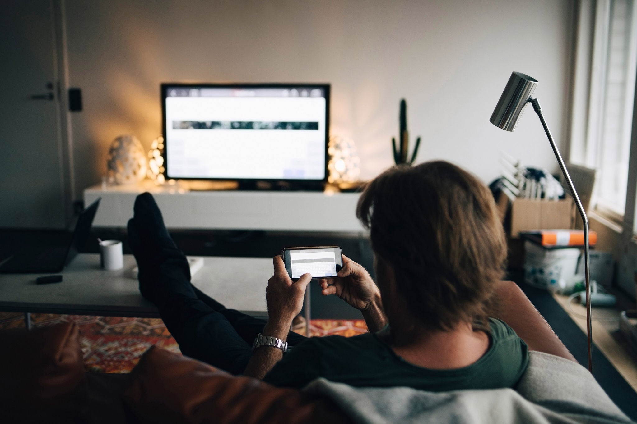 man using mobile phone while sitting on sofa in living room