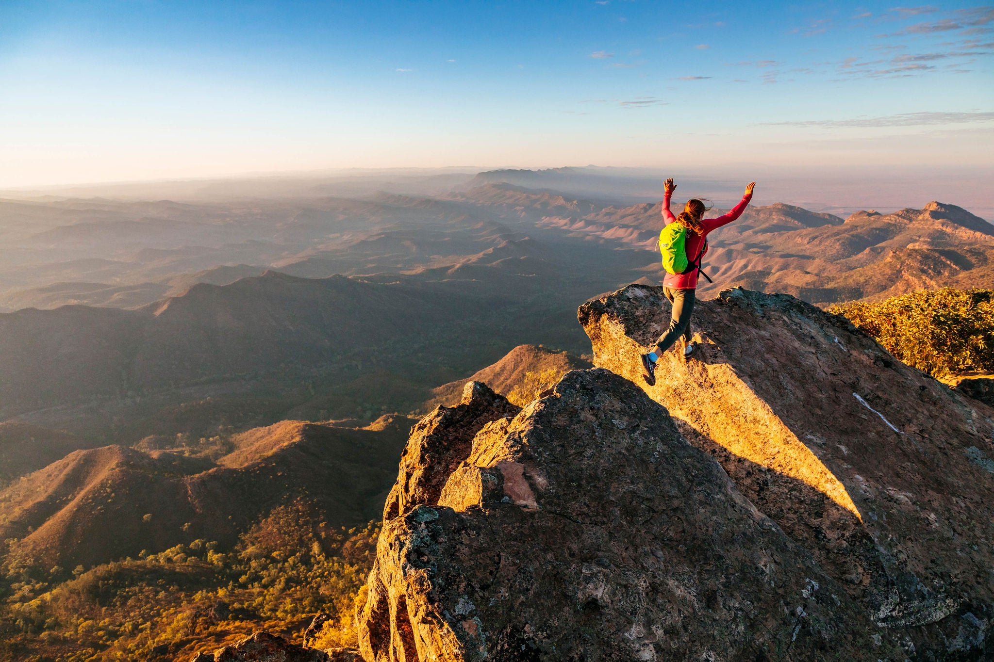 Woman leaps across a gap in the rocky ridge in South Australia