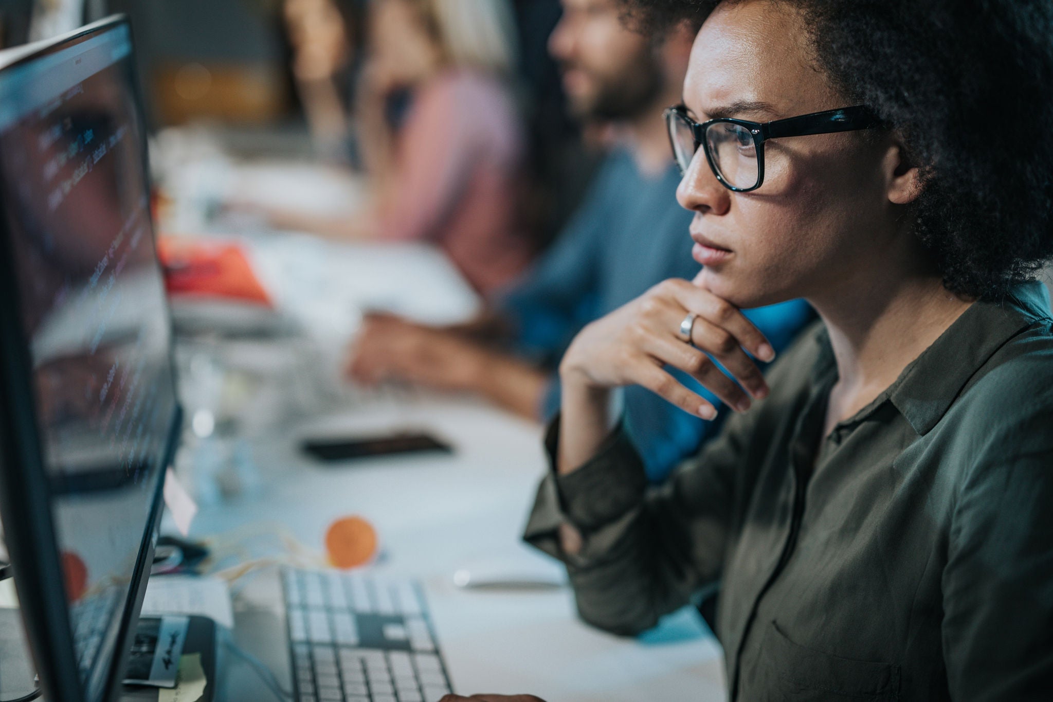 African American female programmer brainstorming while working on computer codes in the office.