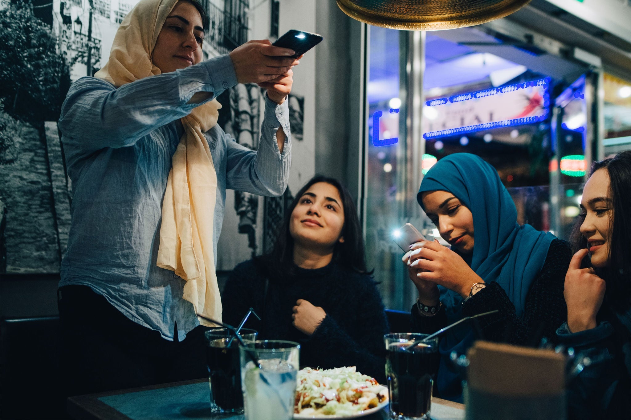 Moslimmeisjes fotograferen eten in een café.