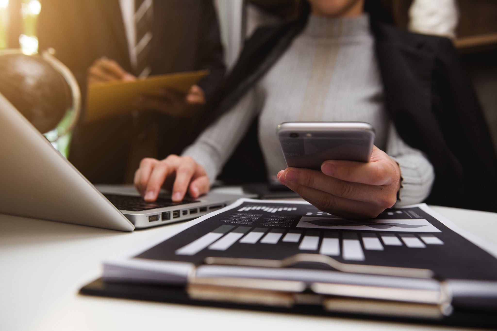 Woman analyzing data on phone and laptop