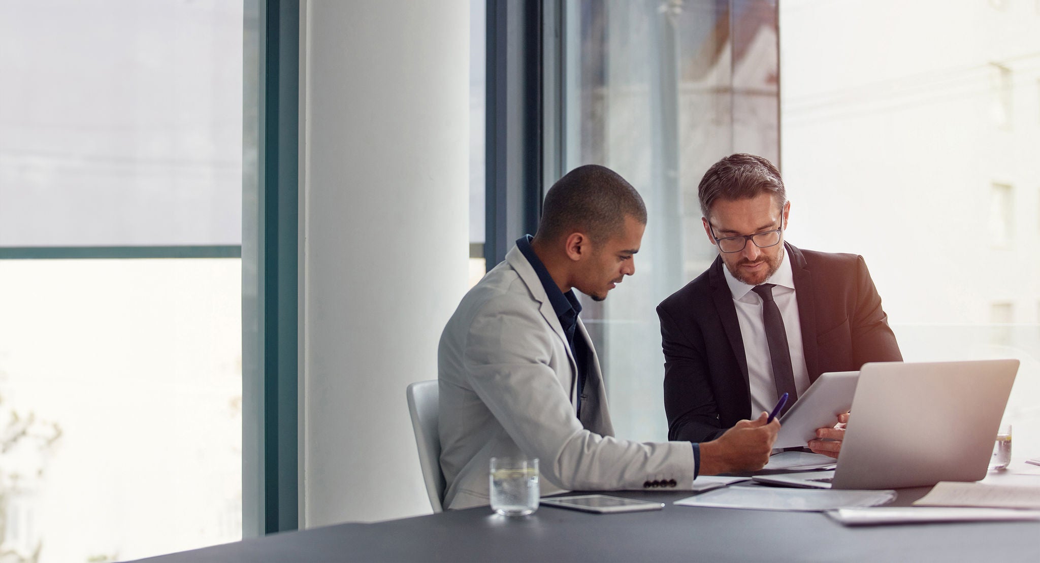 Tablet, laptop and business men planning in conference room meeting, teamwork and discussion of corporate data. Professional people or partner talking, review or report analysis on digital technology.