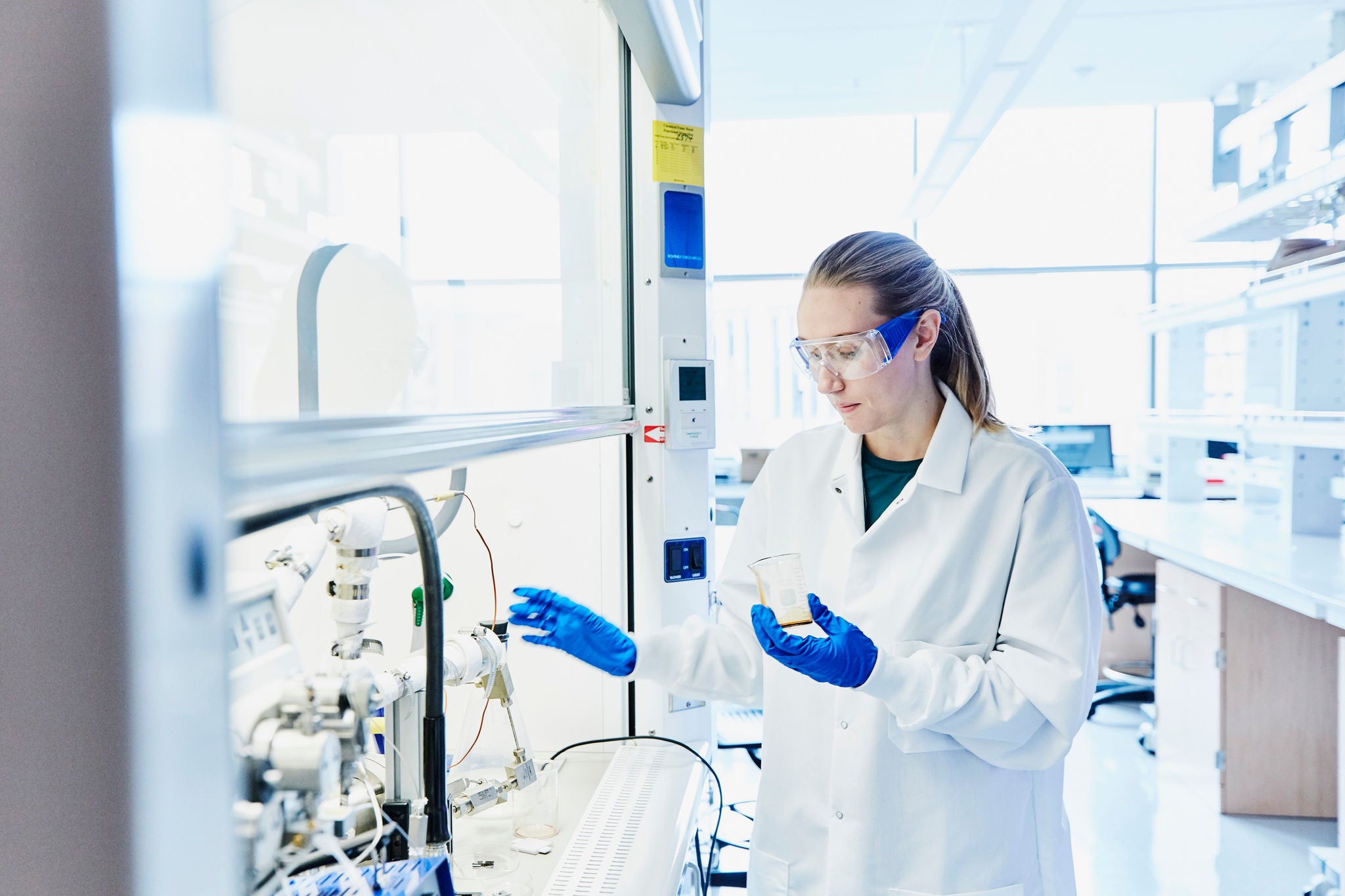 Female scientist working on experiment in fume hood in laboratory