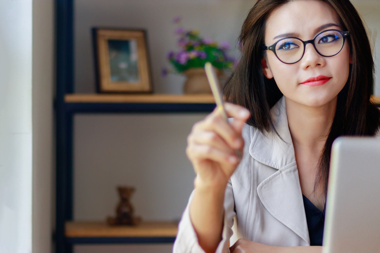  A lady holding a pen and placed laptop infront