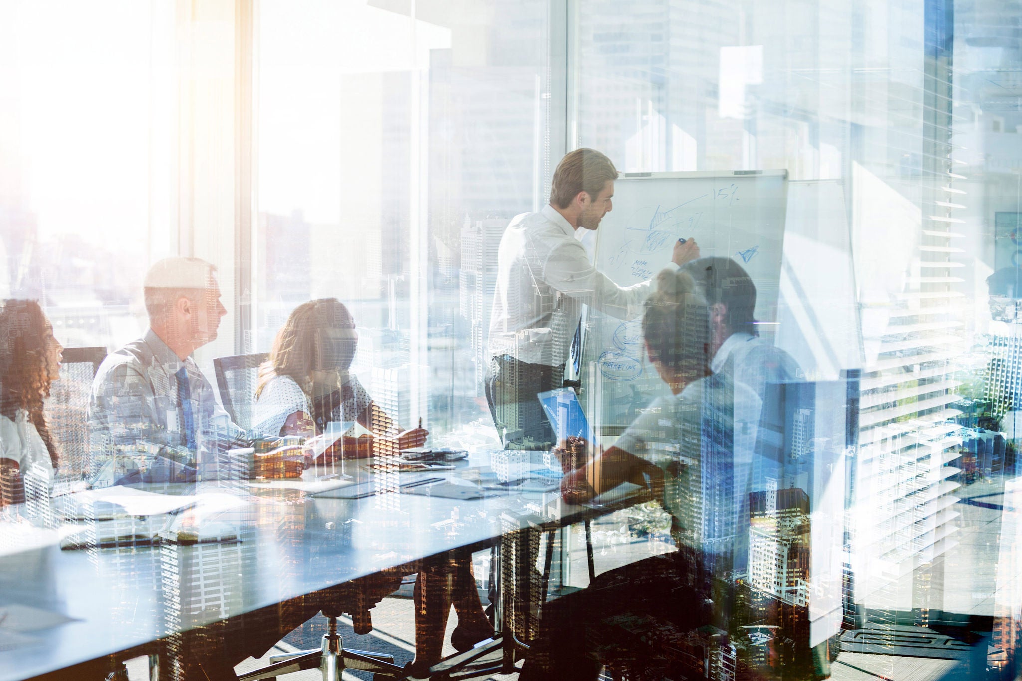 Montage of a team of business people at a presentation at the boardroom table. There are several buildings in an overlaid cityscape. There is also motion blurred traffic on a roadway in the middle of the group. City is Sydney, Australia. Business development; growth and architecture