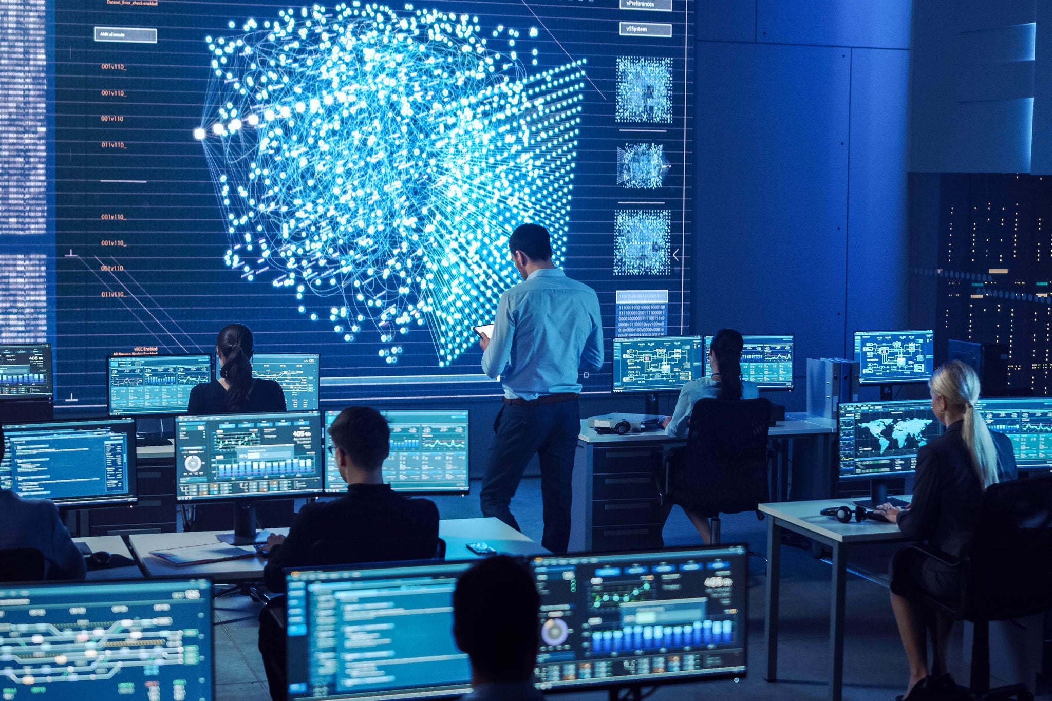 Team of Professional Computer Data Science Engineers Work on Desktops with Screens Showing Charts, Graphs, Infographics, Technical Neural Network Data and Statistics. Dark Control and Monitoring Room.