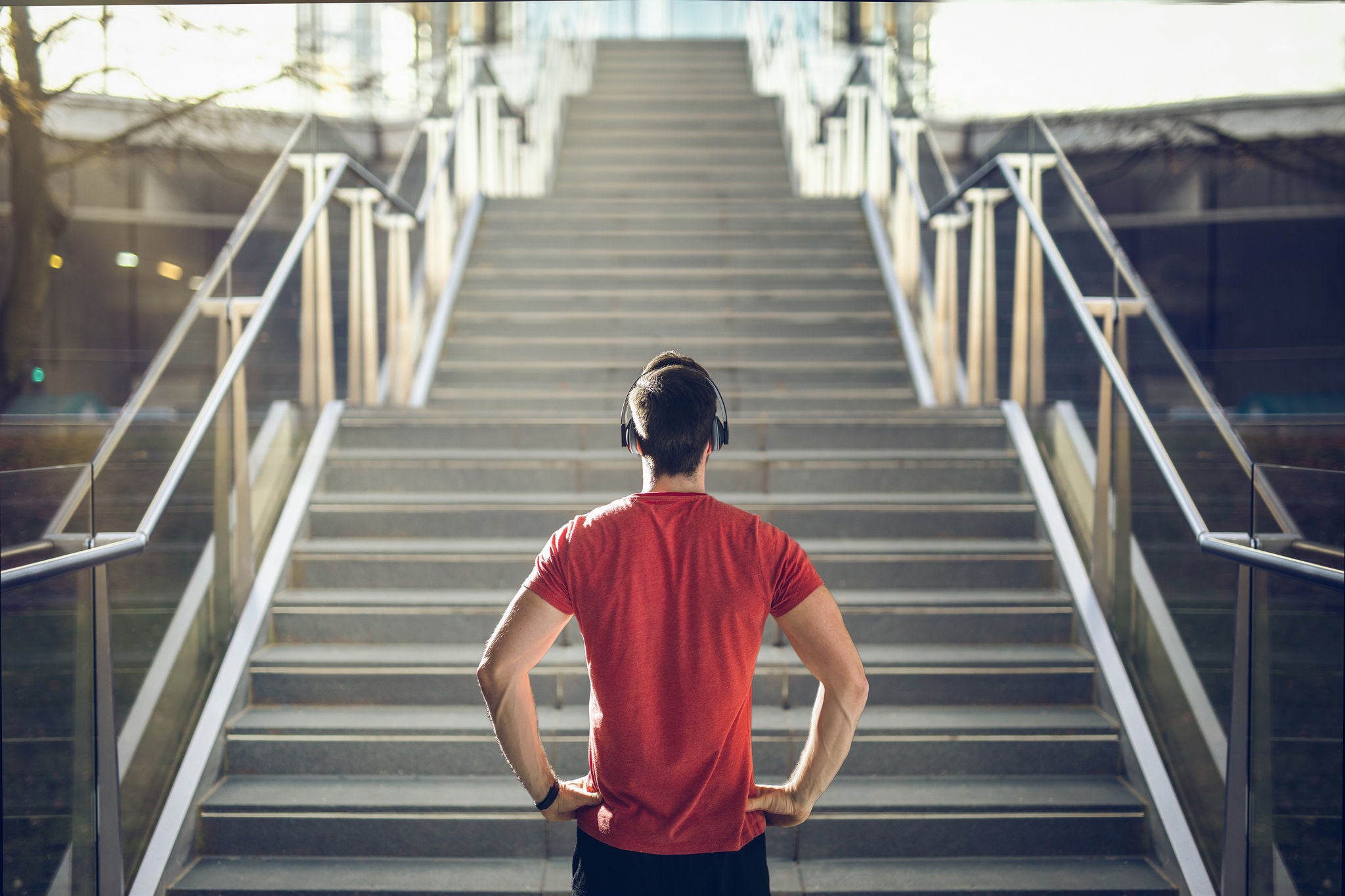 Man in red shirt preparing for stair run at sunset.