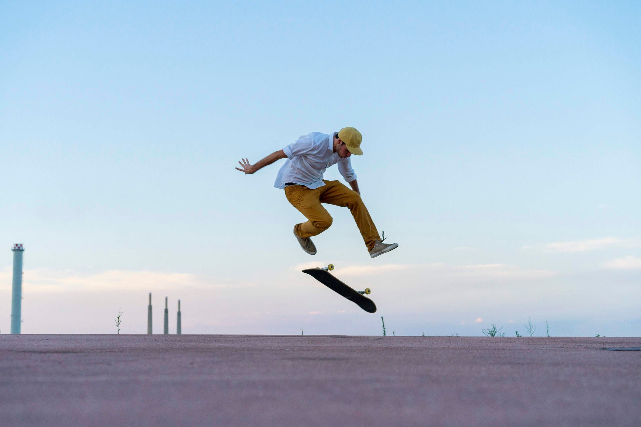 Young man doing a skateboard trick on a lane at dusk