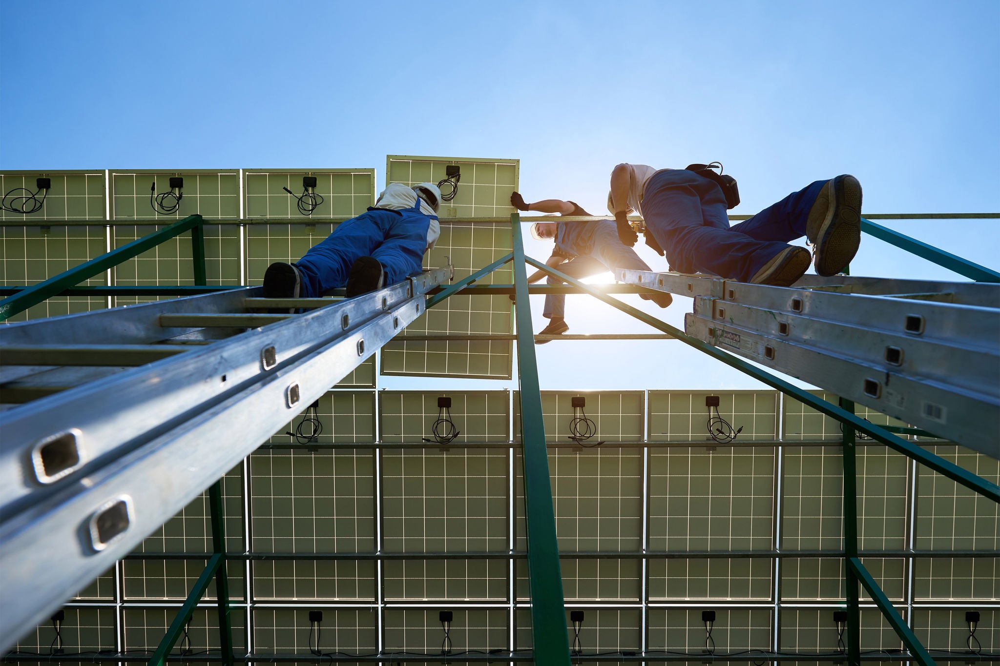 Solar panels mounting work ending by professionals workers team. Using special equipment, providing new technologies ecology saving, green energy solution. High-tech exterior,smart building. Ladder.