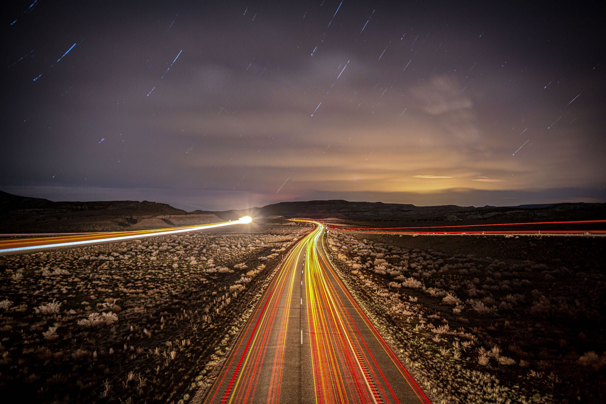 Long exposure image of an interstate highway at night with star trails in the sky