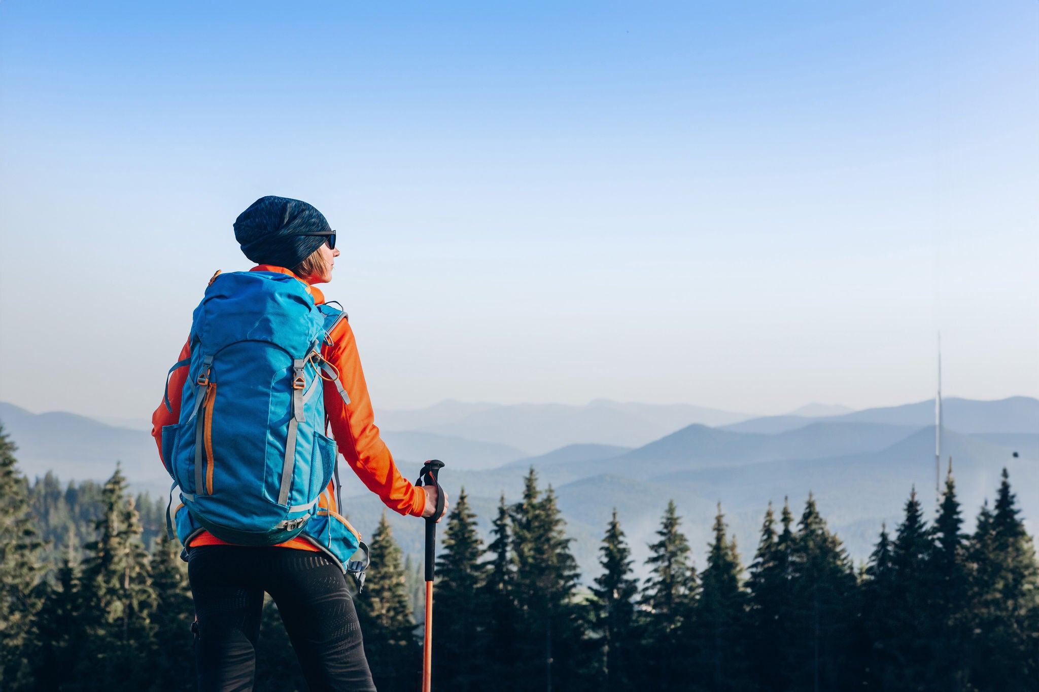 Woman hiker standing on the top of mountain ridge against mountains