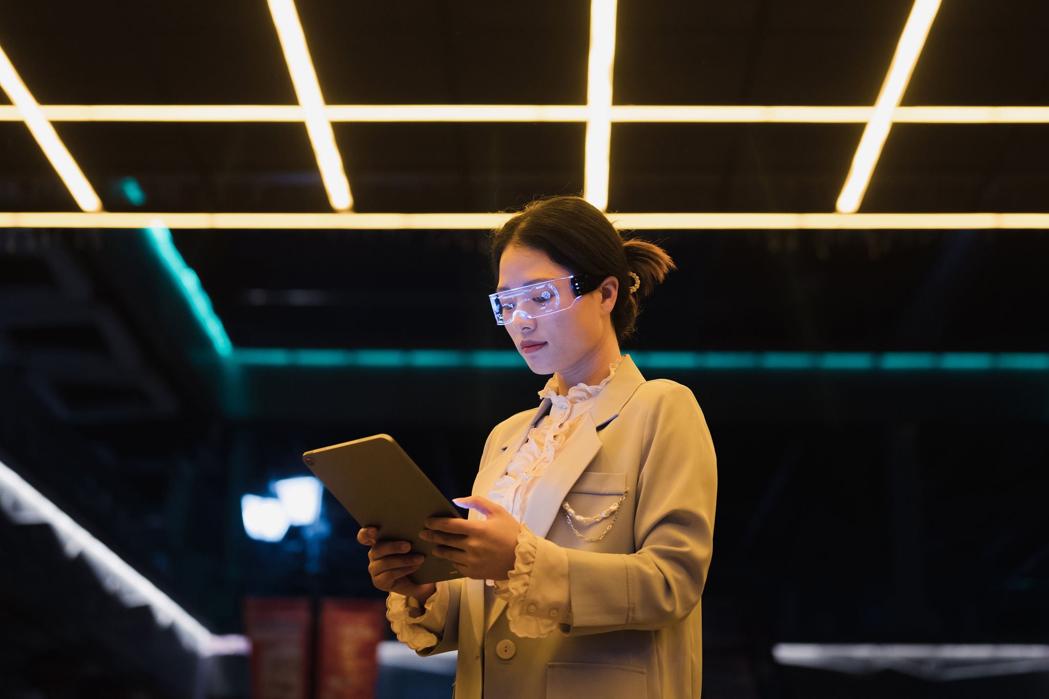 woman wearing augmented reality glasses using tablet at night