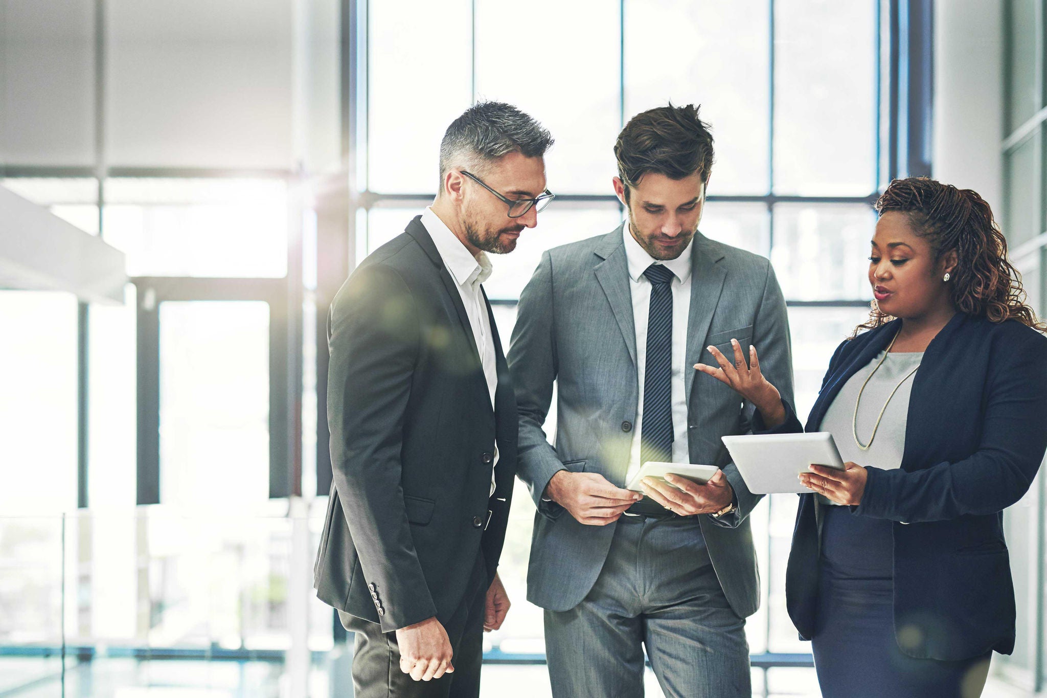 Shot of a group of coworkers talking together over a digital tablet in an office