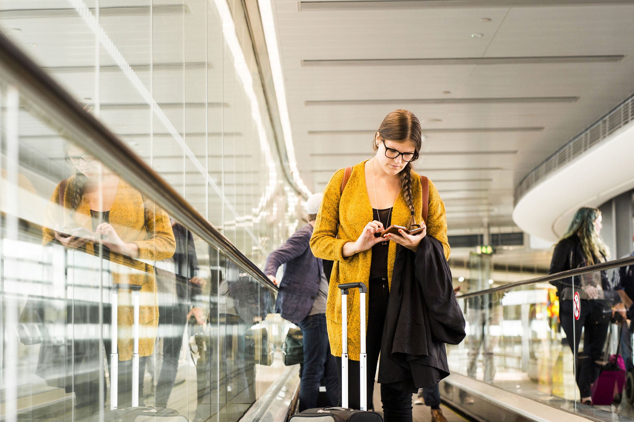 businesswoman-smart-phone-moving-walkway-airport.