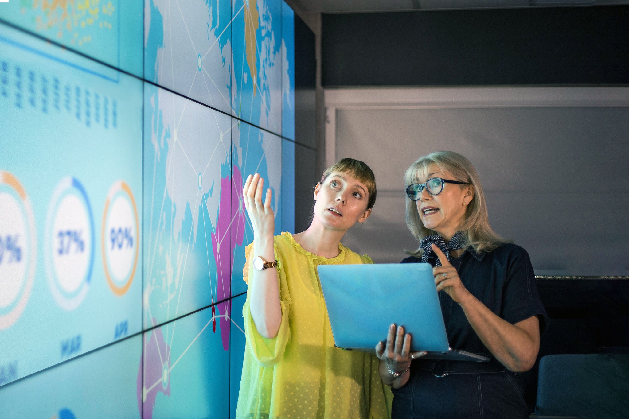 ey-businesswomen-discussing-ideas-at-information-wall