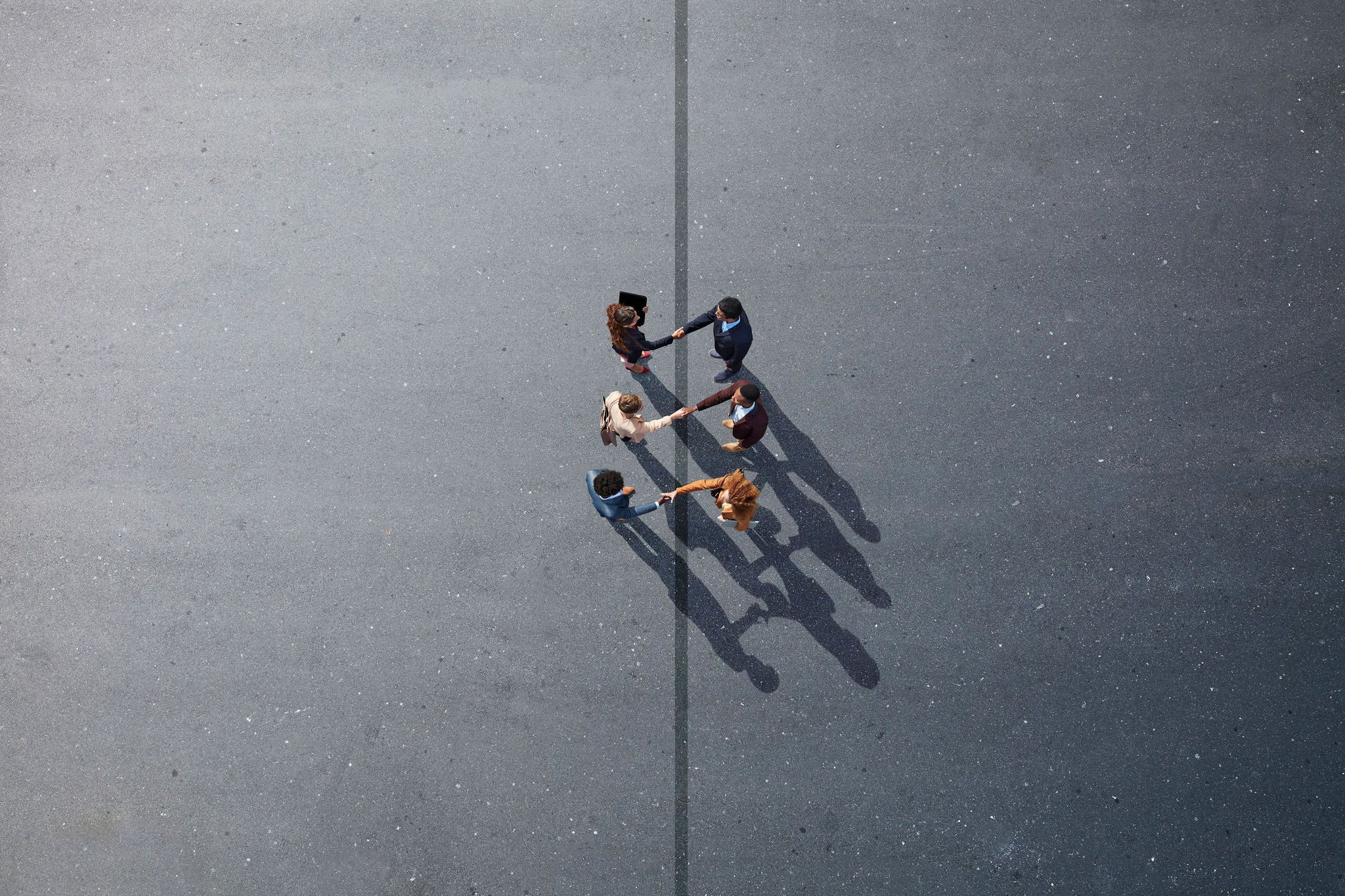 Businesspeople making handshakes across line, on painted asphalt