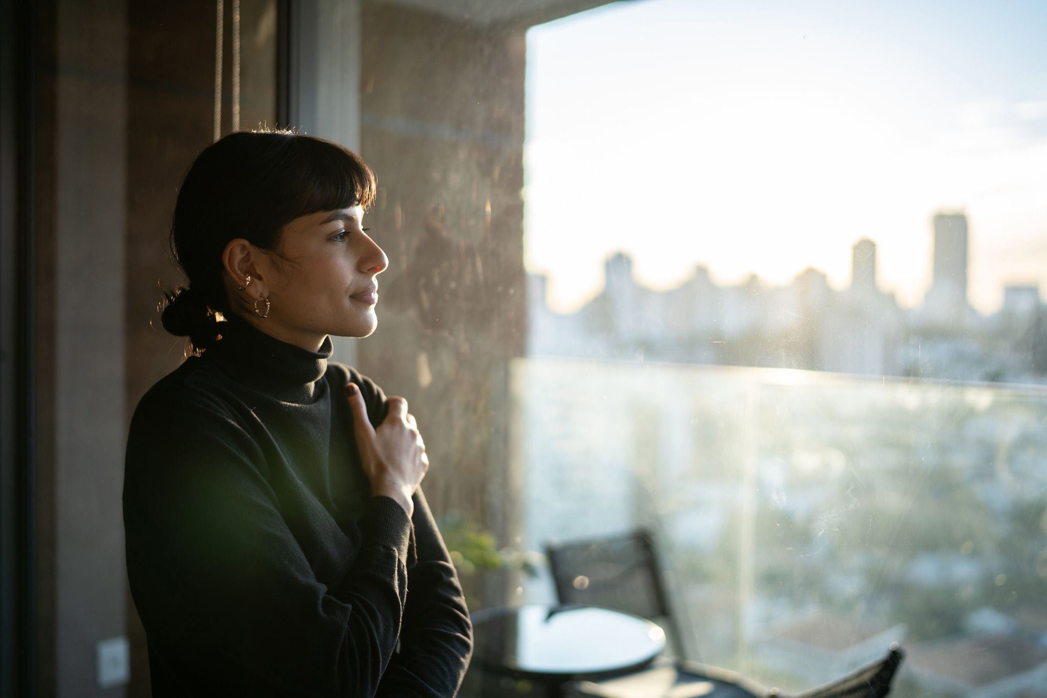 Young woman looking out her window at home