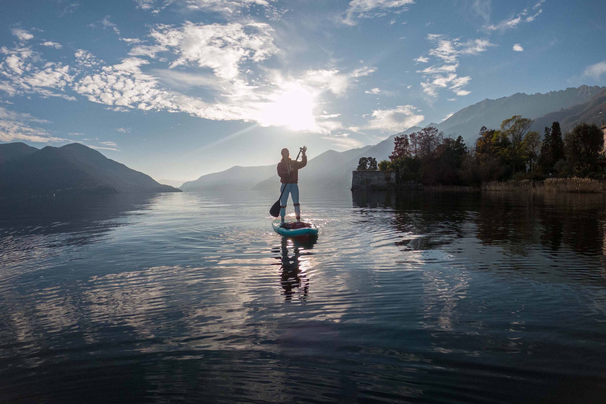 A person balances on a paddle board, surrounded by calm water, enjoying a serene day outdoors.