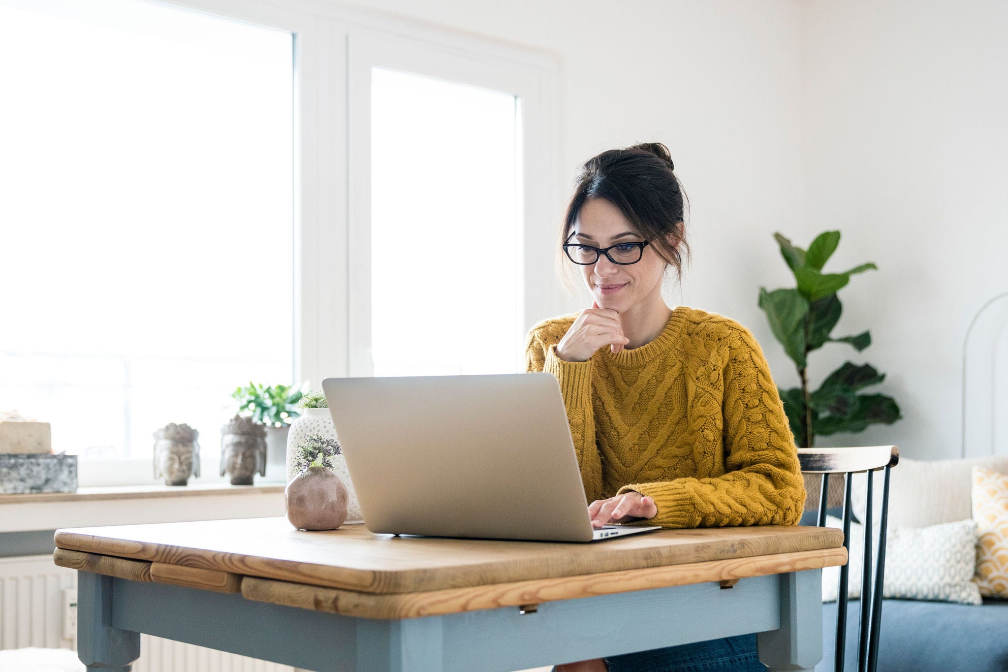 young woman with a laptop wearing yellow jumper