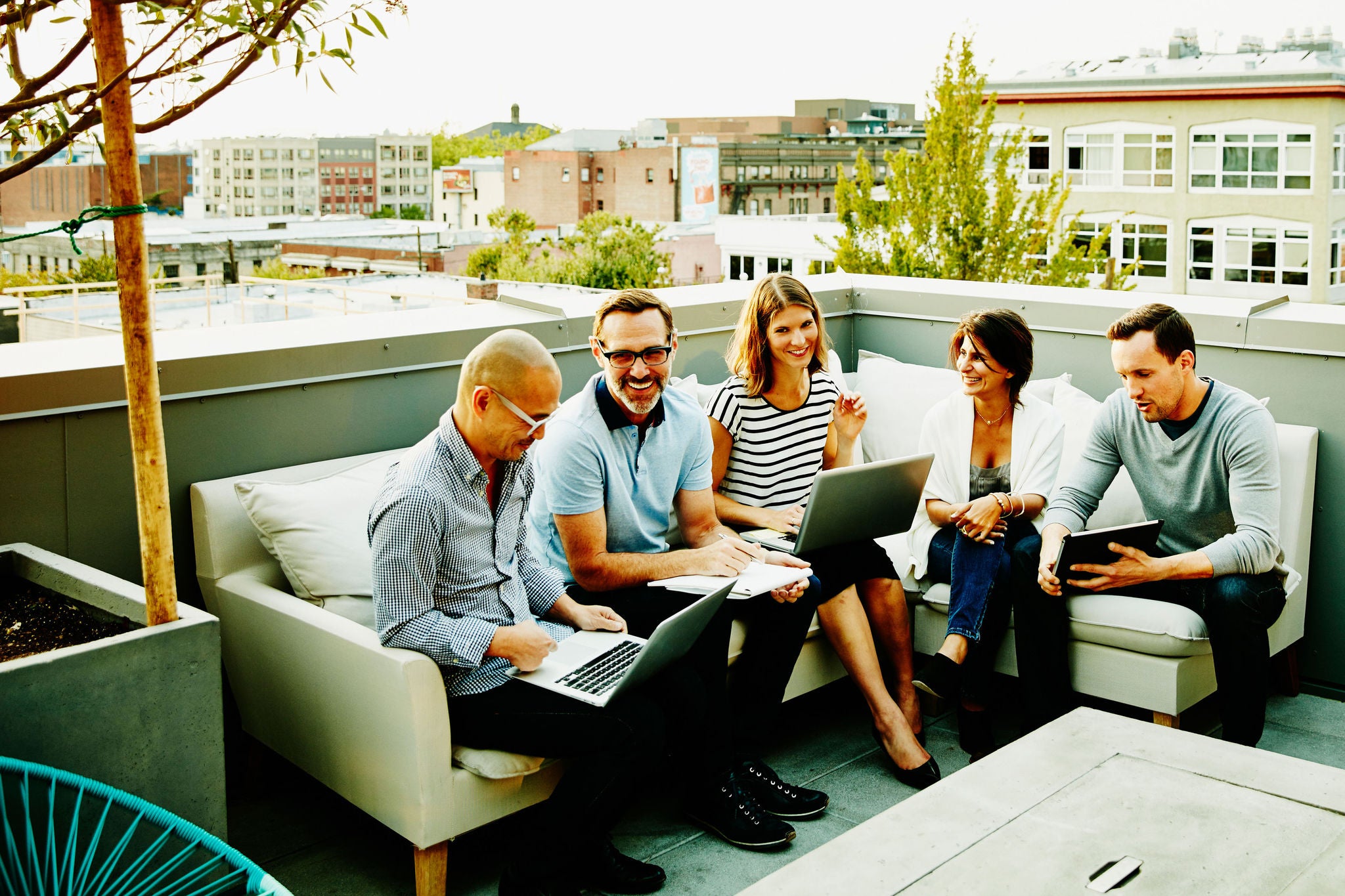 Smiling group of colleagues having informal meeting on terrace of office building