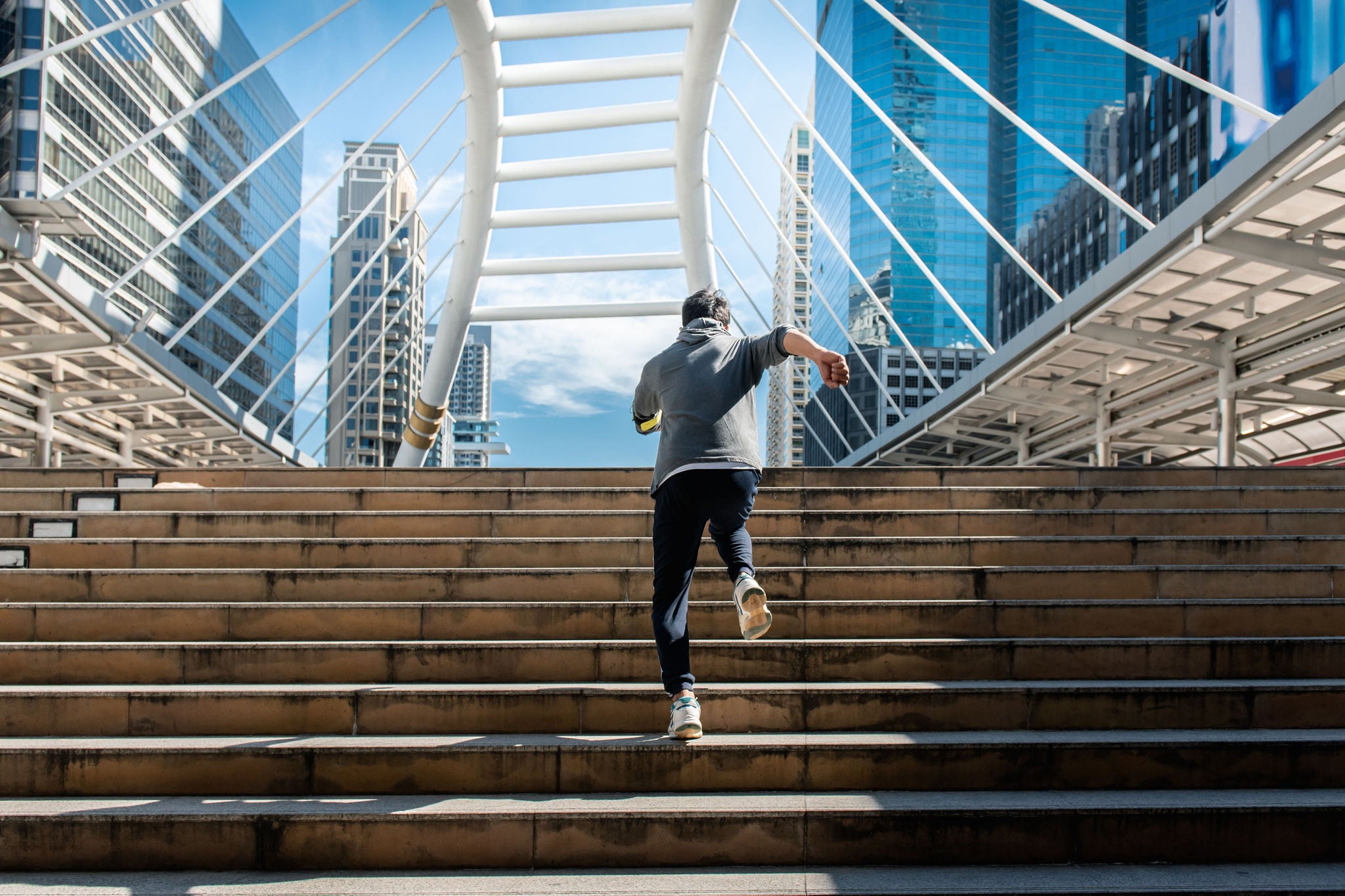 man running up stairs towards bridge