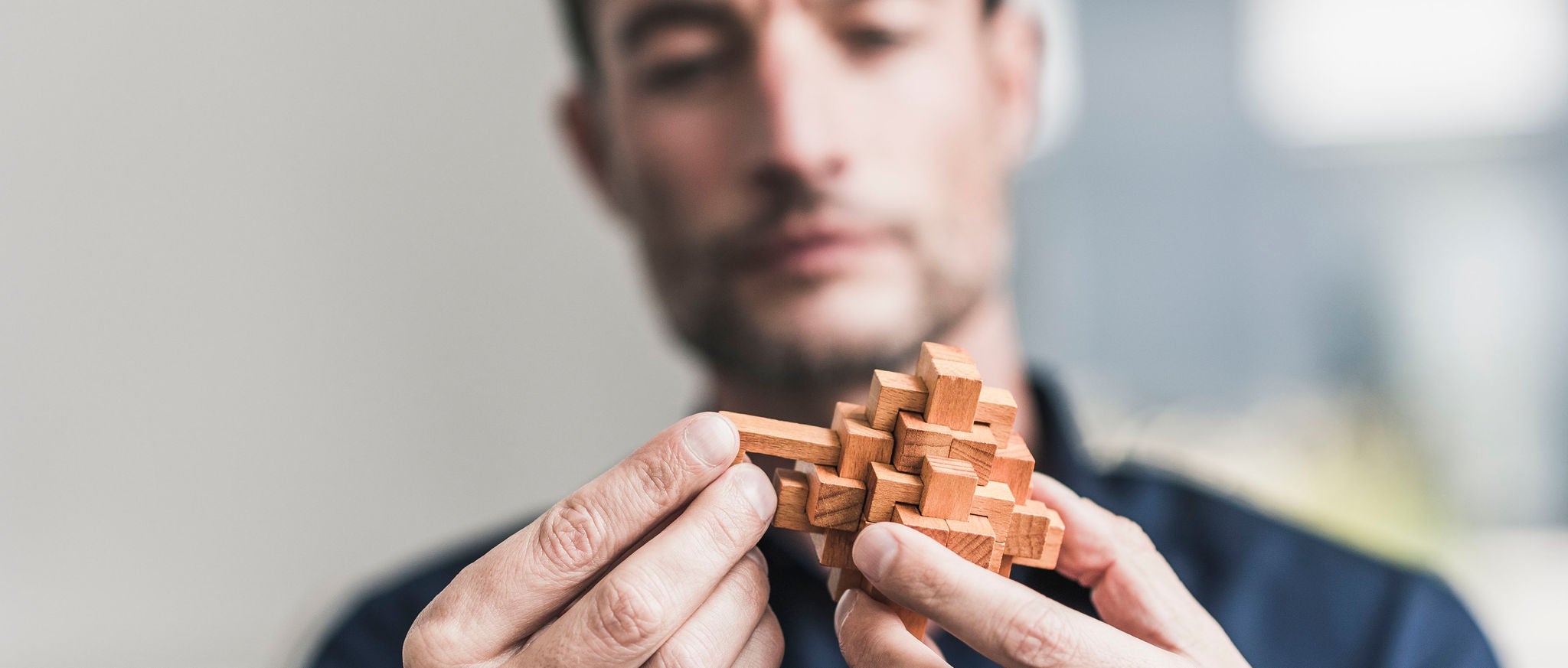 Ã lterer Mann sitzt im BÃ¼ro und baut ein HolzwÃ¼rfelpuzzle zusammen