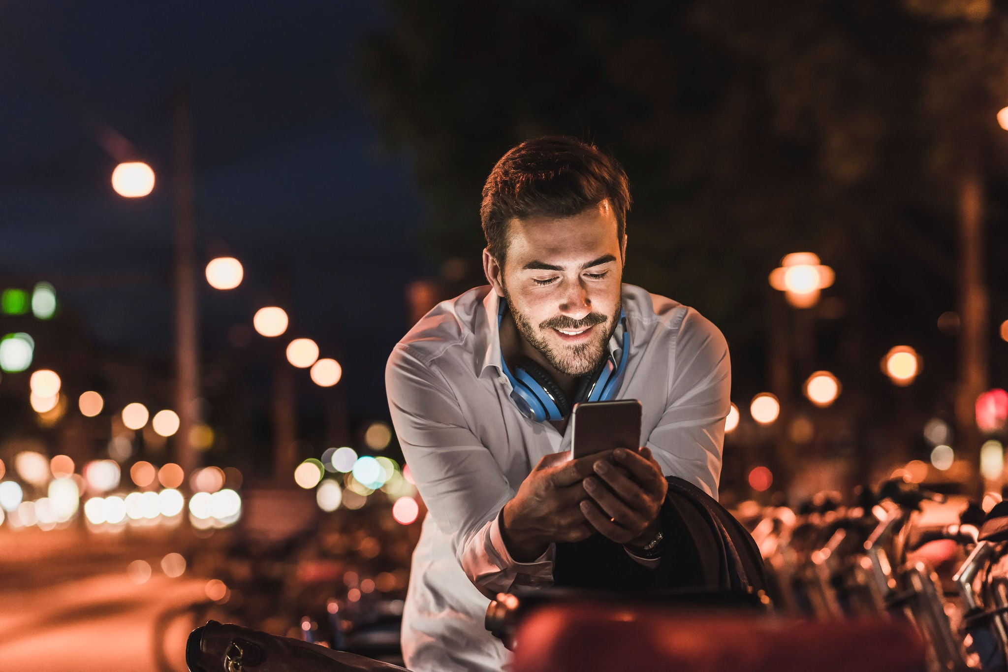 Young man in the city checking cell phone at night