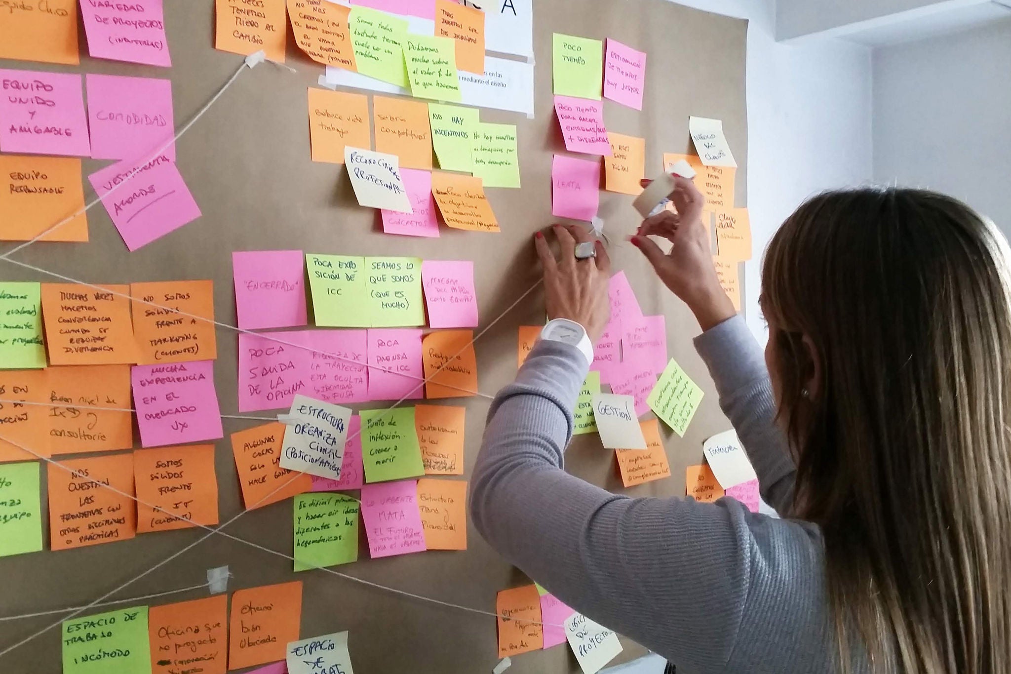 Mujer reordenando post-its sobre una pared de corcho