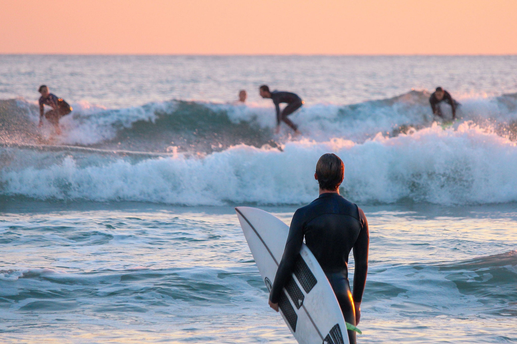 surfer watching his friends surfing from the shore