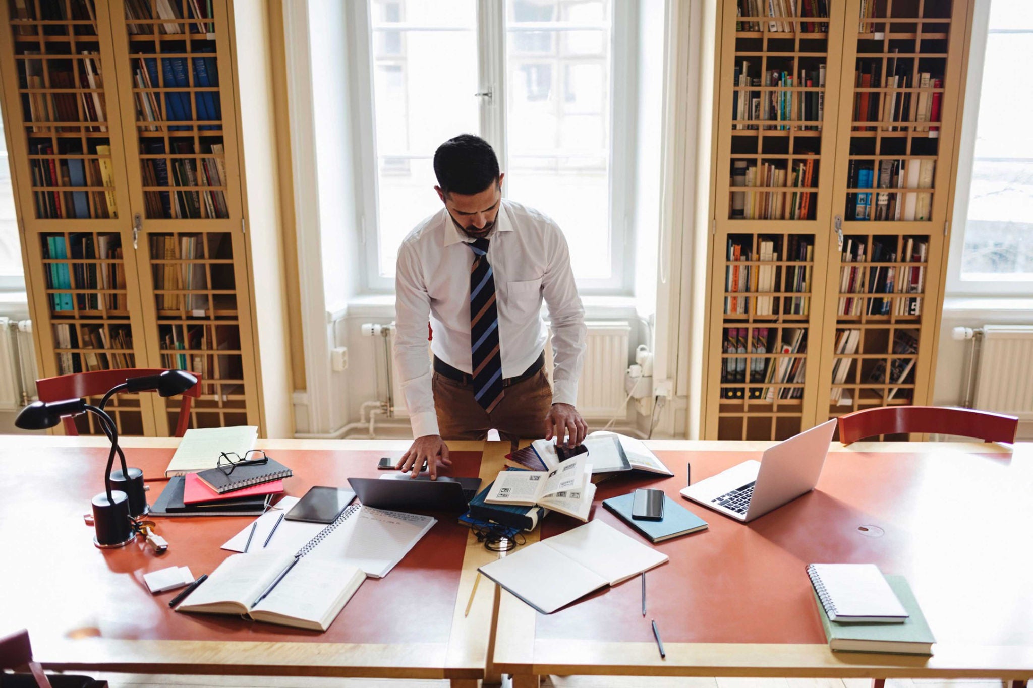 Man researching while standing at table in home library