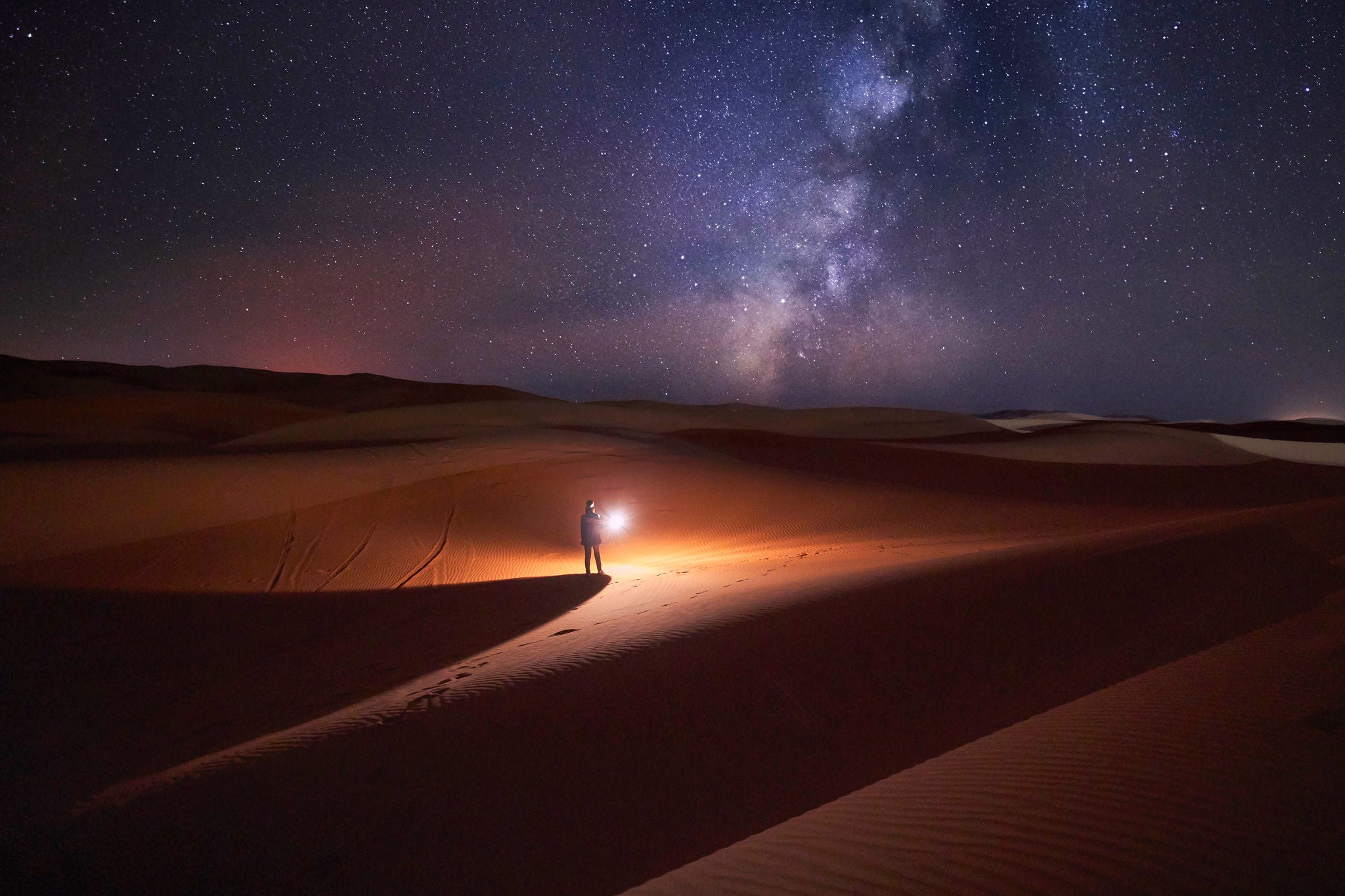 Morocco, Man with light at night in Merzouga desert